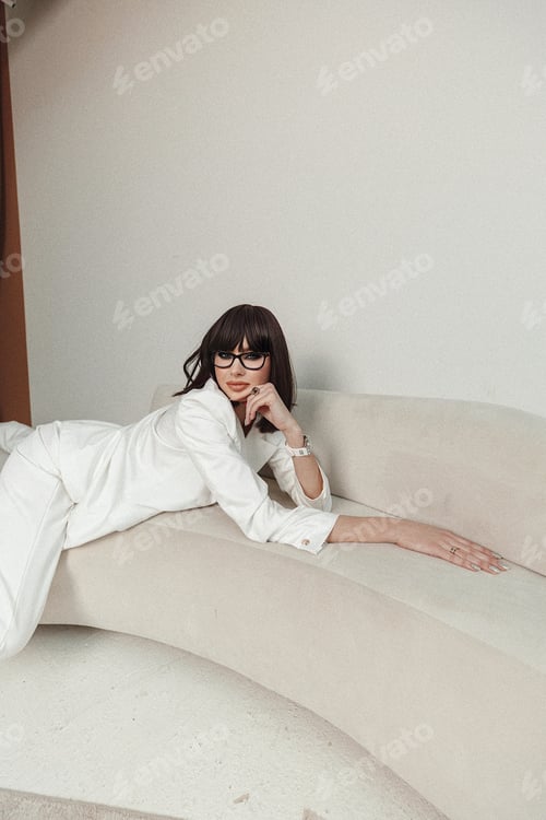 Preview: Stylish Woman Posing on Couch in White Suit