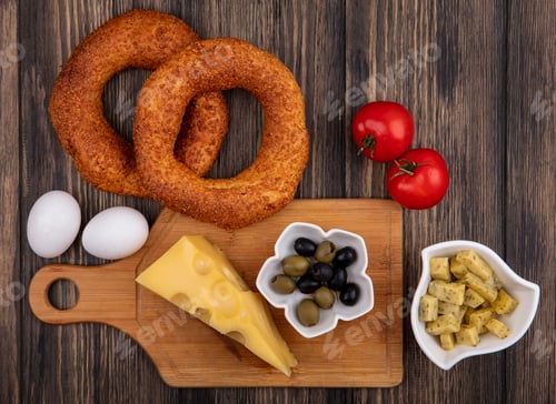 Preview: top view of cheese with olives on a bowl on a wooden kitchen board with eggs and tomatoes isolated
