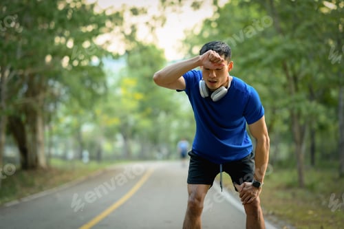 Preview: Shot of tired asian male athlete taking a break, resting after running in the park.