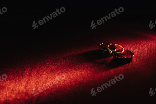 Preview: Two wedding rings and one engagement ring on a red background. three Gold rings of a couple in love
