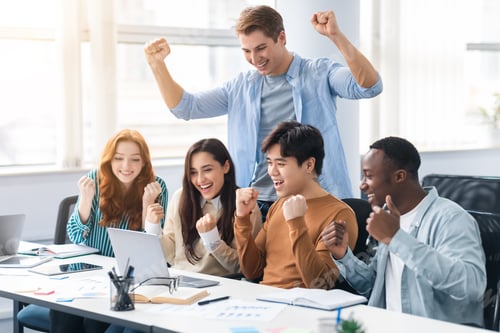 Preview: Group of international people using laptop and shaking clenched fists