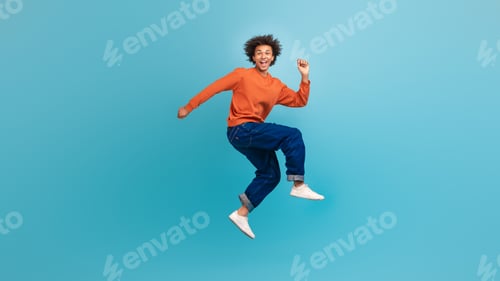 Preview: Young African American man joyfully jumping in a studio environment