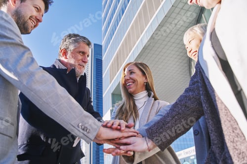 Preview: Group of positive professional coworker people stacking hands outdoors.