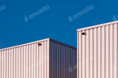 Preview: Two aluminium corrugated warehouse buildings against blue clear sky in perspective side view