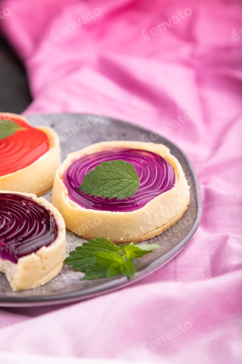 Preview: Sweet tartlets with jelly and milk cream with cup of coffee on a black concrete background