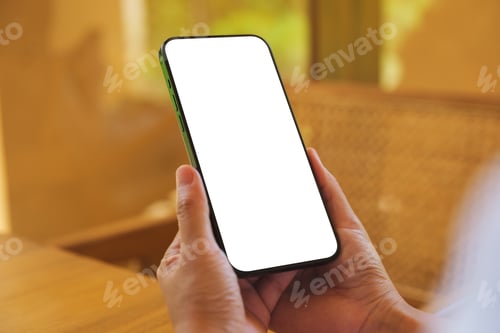 Preview: Mockup image of a woman holding and using mobile phone with blank desktop at home