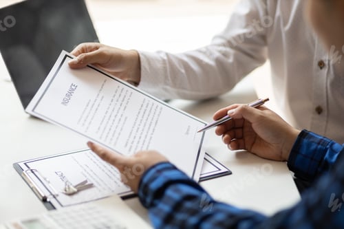 Preview: Man in office showing an insurance policy and pointing with a pen where the policyholder must to sig