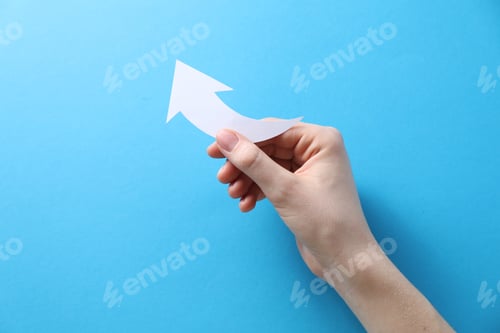 Preview: Woman with paper arrow on light blue background, top view. Space for text