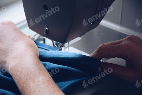 Preview: Seamstress is hemming jeans on sewing machine