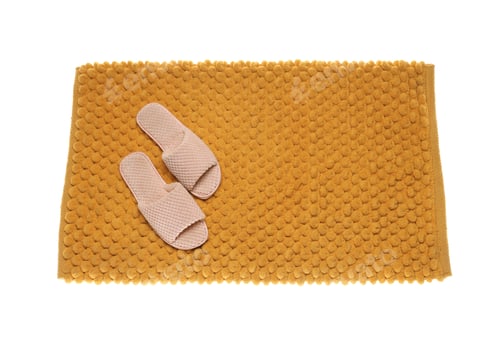 Preview: Soft orange bath mat and slippers isolated on white, top view
