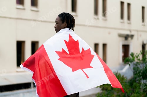 Preview: a black male person holding a flag of canada outdoors, concept of patriotism and independence