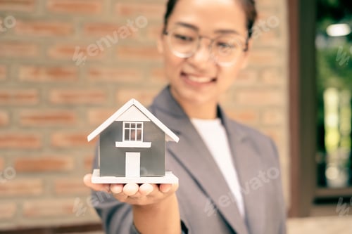 Preview: Home insurance concept and real estate. Businesswoman holding a house model working in investment