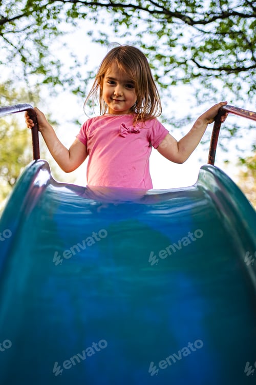 Preview: Joyful child plays on a colorful slide in the park on a sunny da