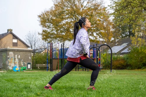 Preview: Healthy woman stretching listening to music at the public park