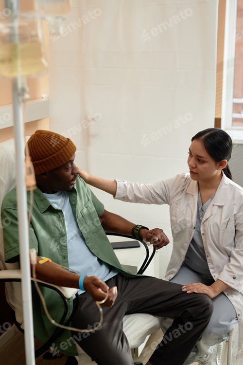 Preview: Caring Nurse Talking to Patient Receiving Treatment in Clinic