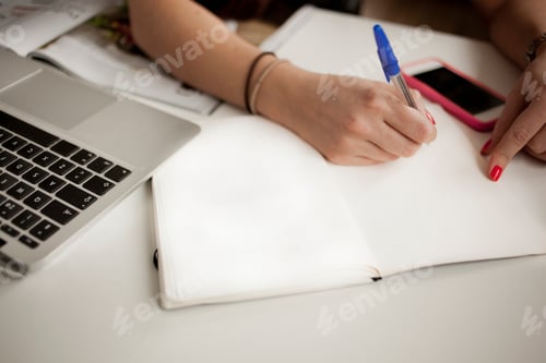 Preview: Cropped image of hands planning in note pad at desk