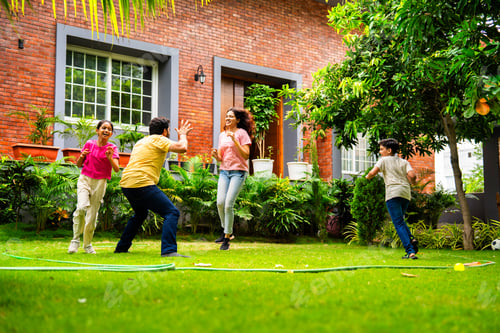 Preview: Indian family playing Langdi or one-leg hop game in garden, enjoying energetic outdoor fun
