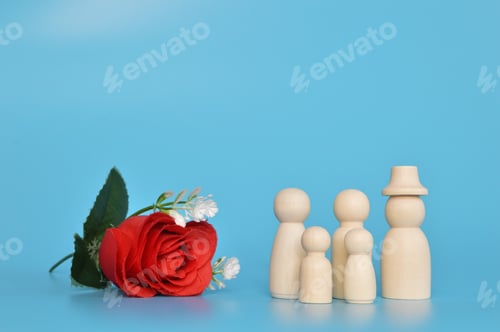 Preview: Wooden doll figures and red flower isolated on a blue background