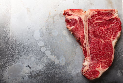 Preview: Raw beef T-bone steak on aluminum tray from above