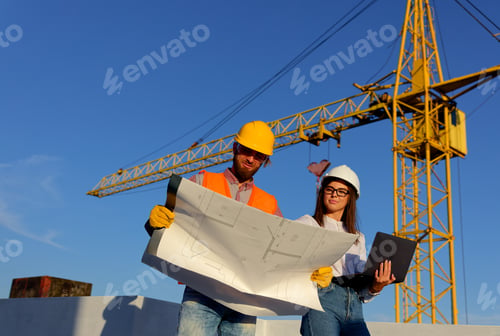 Preview: Construction workers discussing blueprint on building site with crane