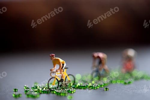 Preview: Miniature Cyclists Racing on a Road of Green Beads — Creative Concept of Sport