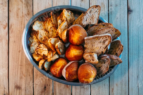 Preview: Basket with assorted bread and muffins on table.