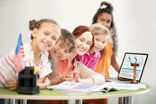 Preview: Teacher and children sitting at the table near laptop
