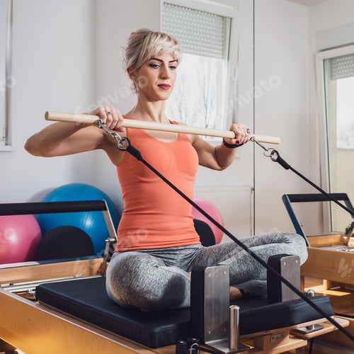 Woman Exercising Using Pilates Reformer Inside a Gym