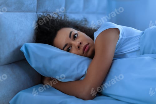 Preview: African lady lying awake alone in her bed at home