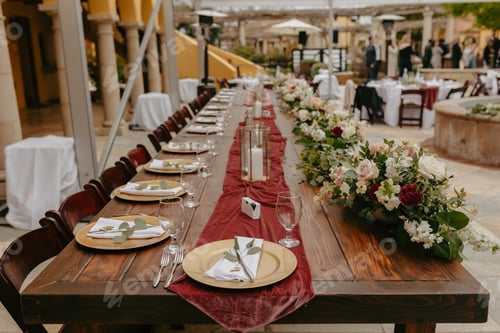 Preview: long table set for dinner at outdoor party setting with red table runner