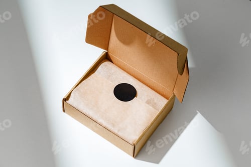 Preview: A small, empty cardboard box with unwrapped parchment resting inside on a bright, sunlit table