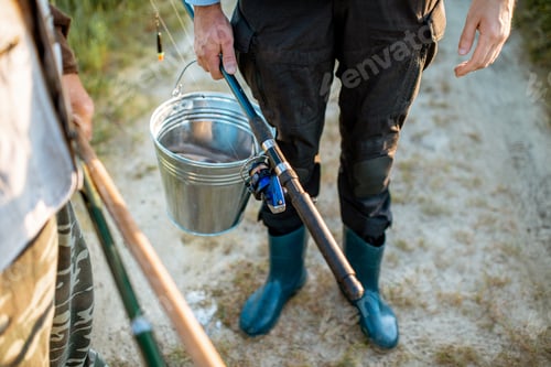 Preview: Holding fishing rods and bucket with fish outdoors
