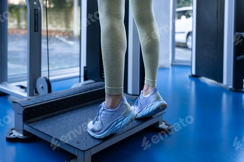 Preview: Woman exercising calves on gym machine wearing sneakers and leggings