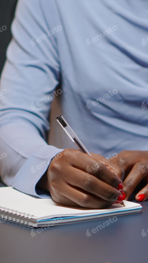 Preview: Close up of african businesswoman writing list of tasks