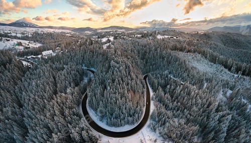Preview: Aerial view of winter landscape with snow covered mountain hills and winding forest road in morning