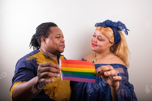 Preview: LGBT couple holds a rainbow flag in hand and they look at each other in love