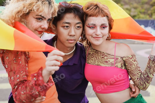 Preview: Young diverse friends having fun with LGBT rainbow flag at pride parade