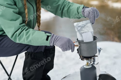 Preview: Young Woman Preparing Food Outdoors Using Portable Gas Stove