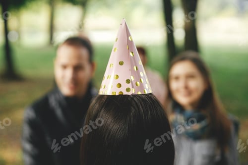 Preview: Stylish pink party hat close up on woman head, back view. Celebrating birthday with family