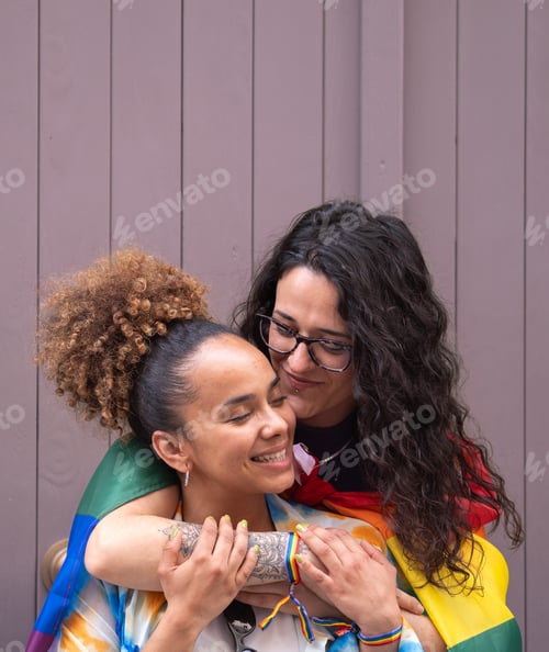 Preview: Young lesbian couple hugging and feeling in love isolated on purple background