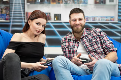 Preview: Portrait of a fun, active couple enjoying playing video games with a console gamepad in their hands