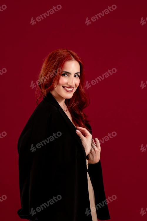 Preview: Confident woman looking at the camera while posing against a red isolated background.