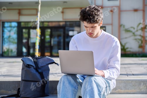 Preview: Young guy college student using laptop outdoor