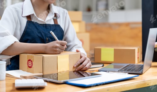 Preview: Shipping shopping online, owner writing address on cardboard box at workplace. small business