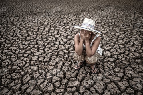 Preview: Women sitting on their hands, closed their faces on dry ground in a warming world.