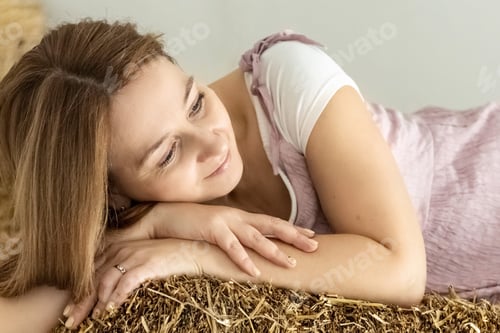 Preview: A smiling young woman in a pink dress is resting in the hayloft .The natural feelings