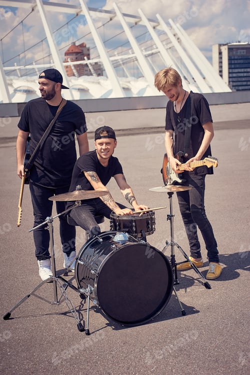 Preview: rock band in black clothing with musical instruments on street
