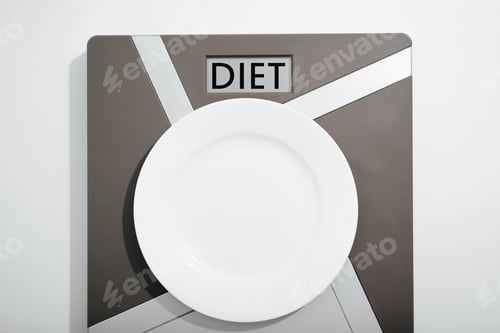 Preview: Diet, weight control concept. Top view empty plate on scales with text on display Diet