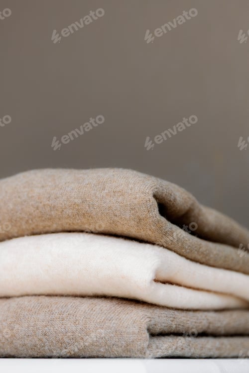 Preview: Three thin warm sweaters on a white shelf.