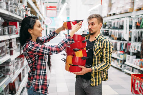 Preview: Young couple buying pans in supermarket